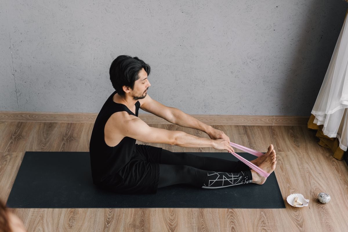 Man stretching with a resistance band on a mat at home